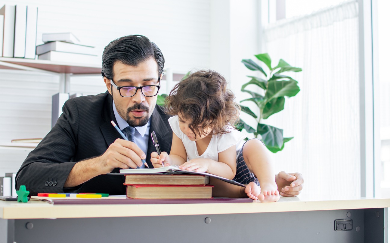 A father working at home, playing and taking care of his little daughter