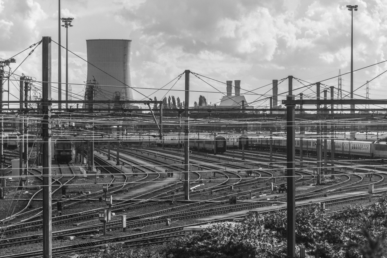 A railway system in the industrial age with a factory cooling tower in the background