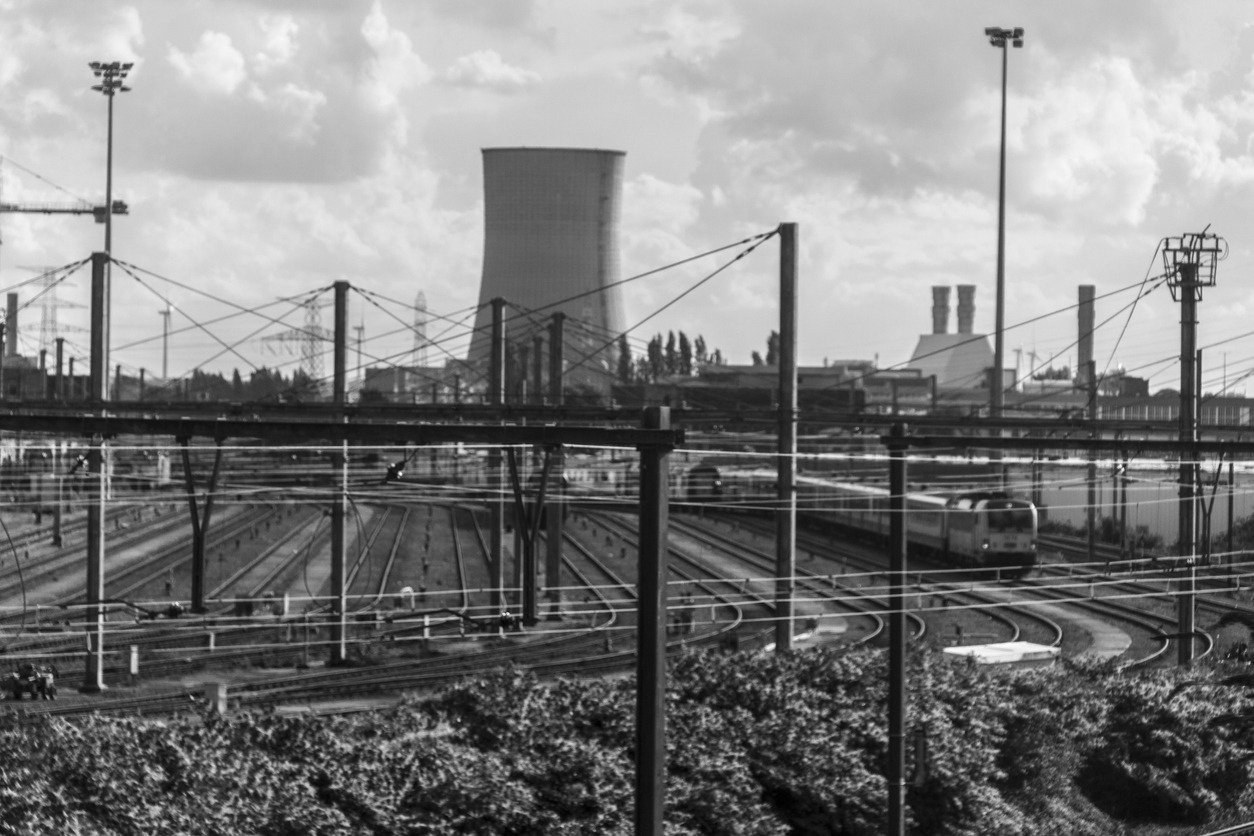 A black and white photo of a city with several factories in the skyline
