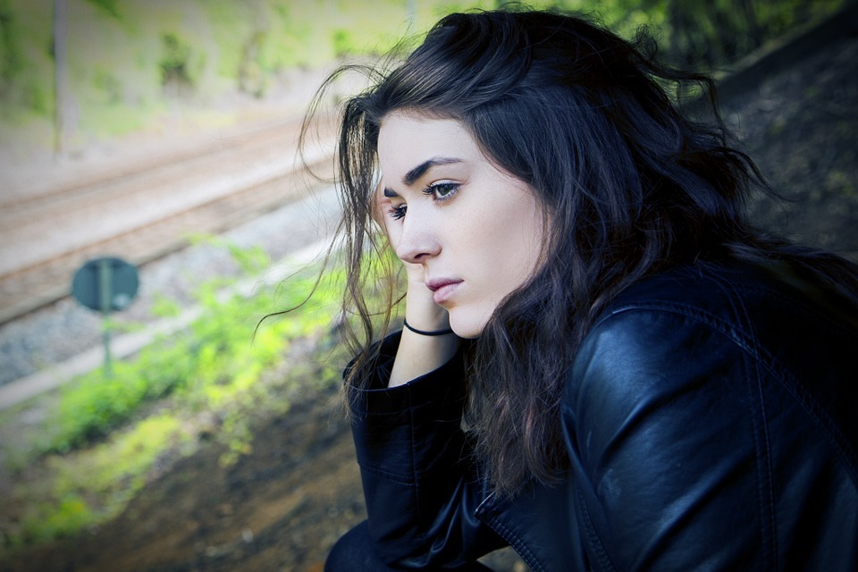 a long-haired woman in a black coat, looking sad