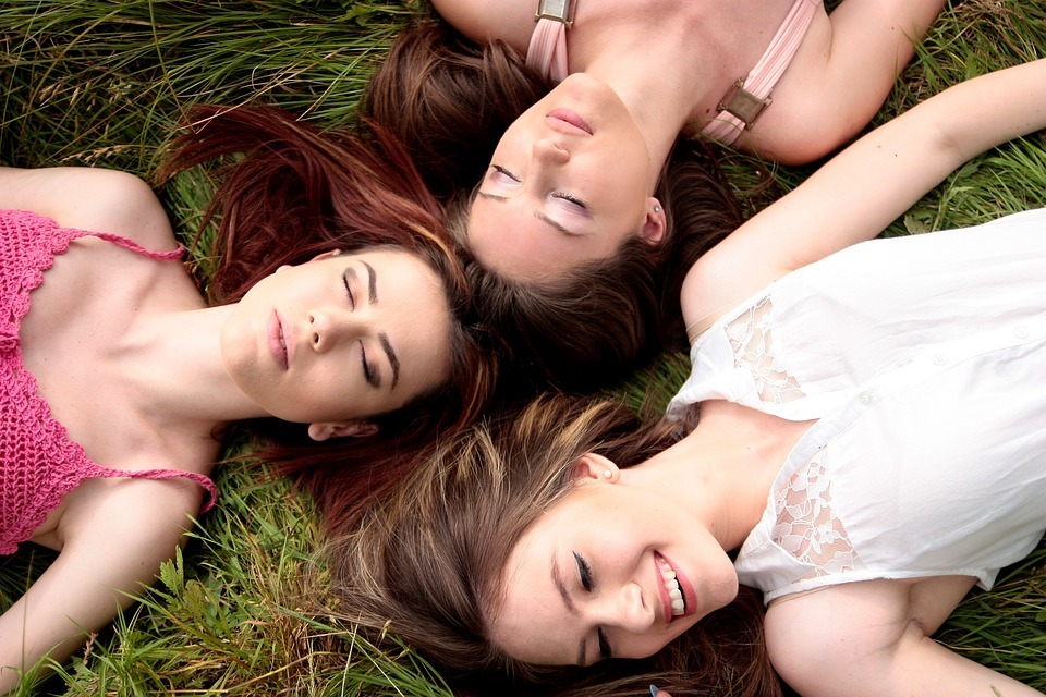 women lying on the ground, some are meditating, and one is smiling