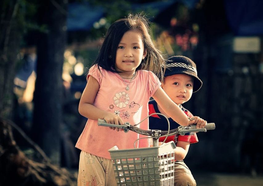 A girl and a boy on a bike, smiling