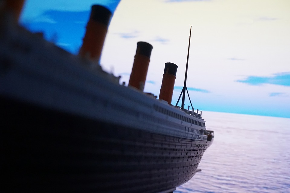 miniature replicate of the Titanic, vast blue ocean, clouds
