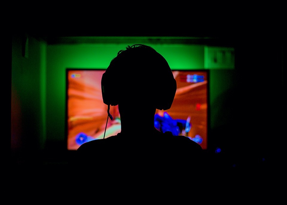 silhouette of a man, pc monitor, man gaming, gamer wearing gaming headset, dark room, neon green led lights