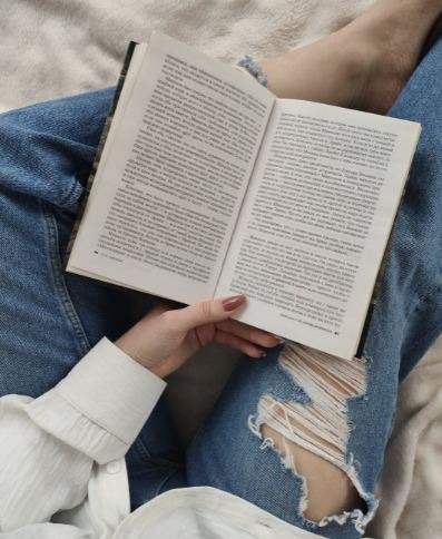 crop-faceless-woman-reading-book-on-bed